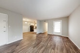 This single-floor residence in East Ridge, Tennessee offers a practical and well-organized layout designed for comfortable living. The open living area greets you upon entry, showcasing rich, dark wood-look vinyl flooring, neutral gray walls, and a textured ceiling that carries throughout much of the home. A light-filled entry door with a paneled window brings in natural light, creating a bright and welcoming atmosphere.

The kitchen is positioned adjacent to the living space in an open, semi-connected layout. It features white cabinetry, dark countertops, a black refrigerator, and a stainless steel sink, providing a clean and functional workspace. A peninsula-style counter separates the kitchen from the living area, enhancing the sense of flow between spaces.

The bedrooms are carpeted with a neutral, soft-toned carpet and include closet storage. One bedroom features a window overlooking greenery, adding a touch of natural scenery. A hallway connects the sleeping areas to a bathroom equipped with white cabinetry, a dark countertop vanity, a medicine cabinet mirror, and wood-look flooring.

Additional areas visible from the layout include a secondary living or flex space and a corridor leading to private rooms. Throughout the home, consistent neutral tones, clean finishes, and functional design elements create a cohesive and move-in-ready environment.
