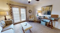 Located at 8301 N Council Rd in Oklahoma City, Oklahoma, this single-floor residence offers a comfortable and functional layout. The living area serves as the heart of the space, featuring plush wall-to-wall carpeting, a textured ceiling, and a ceiling fan with a light fixture that provides both comfort and illumination. A set of French doors floods the room with natural light while offering access to the outdoors, complemented by patterned curtains and horizontal blinds for privacy. The living area is generously proportioned, providing ample room for seating and relaxing arrangements. Adjacent to the living space is a galley-style kitchen outfitted with warm wood cabinetry, granite-look countertops, a stainless steel sink, and black appliances including a refrigerator and range. Wood-look flooring adds a practical, easy-care surface underfoot. The bathroom continues the wood-look flooring and features a granite-topped vanity with matching wood cabinetry, a full bathtub with shower, and clean white walls accented with decorative touches. The bedroom, visible in the floorplan view, offers carpeted flooring and connects conveniently to the rest of the unit. Overall, the space presents a warm, inviting ambiance with a cohesive neutral color palette throughout.