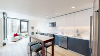 Located in the heart of Oakland at 1950 Broadway, this modern one-bedroom, one-bathroom residence offers a thoughtfully designed open-concept layout with contemporary finishes throughout. Light-toned hardwood flooring flows seamlessly across the entire space, complementing the clean, minimalist aesthetic.

The combined kitchen and living area serves as the centerpiece of the home. The kitchen is equipped with stainless steel appliances, including a range, microwave, dishwasher, and refrigerator. Two-toned cabinetry — matte white upper cabinets paired with slate-grey lower cabinets — frames a striking marble-look backsplash and countertops. A freestanding island with bar seating provides additional prep space and casual dining. The living area benefits from floor-to-ceiling corner windows that frame panoramic views of the downtown Oakland skyline, flooding the space with natural light.

The bedroom is a calm retreat featuring light walls, hardwood flooring, and a sliding-door closet. The bathroom is finished with a marble-surround tub and shower, a dark-grey vanity with a white countertop, and an LED-lit mirror, completing the modern design language found throughout the residence.