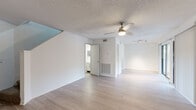This two-story residence is designed with a clean, neutral aesthetic carried consistently across both floors. The main level features light wood-style flooring throughout its open living areas, complemented by textured ceilings and ceiling fans that enhance airflow and comfort. A staircase connects the two floors, as visible in the 3D layout. The living room is a standout space, anchored by a tile-surround fireplace and featuring track lighting and access to an outdoor area via sliding glass doors, allowing natural light to flow in. An adjacent open area provides flexible use of space.

The kitchen has been thoughtfully updated with white upper cabinetry, grey lower cabinets, white quartz countertops, a subway tile backsplash, and a full suite of stainless steel appliances including a refrigerator, range, microwave, and dishwasher.

Upstairs, the bedrooms are finished with plush carpet and multiple windows that bring in natural light. The primary bedroom connects directly to a en-suite bathroom featuring white shaker-style cabinetry, a single-basin vanity with a framed mirror, and wood-style flooring. Additional bathroom spaces maintain the same bright, clean finishes seen throughout the home.