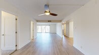 This single-floor residence presents a clean, contemporary aesthetic throughout its well-organized layout. The open living area is a standout feature, finished with light wood-tone flooring that extends seamlessly through the main spaces. A ceiling fan with integrated lighting anchors the room, while large sliding glass doors flood the interior with natural light and provide direct access to a balcony overlooking surrounding buildings and greenery.

The kitchen has been thoughtfully renovated with a two-tone cabinetry design, pairing white upper cabinets with warm wood-finish lower cabinets. A central island with a white countertop offers additional workspace, complemented by stainless steel appliances including a gas range, microwave, dishwasher, and a large side-by-side refrigerator with a built-in water dispenser. A textured tile backsplash and recessed lighting complete the modern aesthetic.

The bedrooms feature neutral carpeting, textured ceilings, and ample closet access, providing a comfortable and quiet retreat. The bathroom is fitted with beige tile work and a glass-enclosed walk-in shower with a handheld fixture. Throughout, the unit maintains a neutral, light-filled palette that contributes to an open and airy overall ambiance.