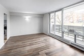 Located at 22 Close Ave in Toronto's vibrant west end, this efficiently designed unit offers a thoughtful layout across a single floor, comprising a living room, kitchen, bathroom, and entrance. The living room is a standout space, featuring large floor-to-ceiling sliding glass doors that open onto a private balcony with glass railings, flooding the room with natural light and providing views of the surrounding neighbourhood. The room is finished with warm wood-tone laminate flooring and neutral walls, creating a clean, modern aesthetic. Adjacent to the living area, the separate kitchen is well-equipped with sleek white high-gloss cabinetry extending to the ceiling, dark granite countertops, a stainless steel refrigerator, and a stainless steel sink, all set over light-toned tile flooring. The bathroom features a full soaker tub with an overhead shower, white subway tile surround, and a decorative mosaic accent border in warm earth tones, lending a polished finish. Additional rooms feature the same wood-tone laminate flooring, maintaining a cohesive look throughout. Clean white walls and consistent finishes give the entire unit a bright, move-in-ready feel suited to comfortable urban living in Toronto.