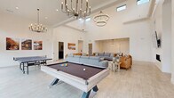 Located in Spanish Fork, Utah, this single-story community clubhouse is a well-appointed facility designed to serve as a social and professional hub. The space features an open, airy layout with light wood-look flooring throughout and a crisp white color palette that contributes to a clean, contemporary aesthetic.

The centerpiece of the facility is a dramatic game room with soaring ceilings, floor-to-ceiling windows, and large sliding glass doors that flood the space with natural light and offer views of the landscaped exterior. Statement chandelier lighting anchors the room, which accommodates both a pool table and a ping pong table. Landscape artwork adorns the walls, adding warmth to the bright interior.

Adjacent to the game room is an expansive lounge area featuring a linear fireplace, plush seating arrangements, and an oversized spherical chandelier, all beneath impressively tall ceilings. This space flows naturally into a secondary lounge with additional seating and a wall-mounted TV.

A dedicated private theater room provides tiered rows of leather reclining sofas, ceiling-mounted projector, surround sound, and classic movie poster décor for an immersive cinematic experience.

Two private offices are thoughtfully furnished with modern desks, guest seating, and nature-inspired wall art, each bathed in natural light from black-framed windows. The hallway connects all areas and features Amazon Hub package lockers alongside separate men's and women's restrooms.
