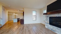 Located at 1511 Wisconsin Ave in Grafton, Wisconsin, this two-story residence offers a well-designed layout spread across two thoughtfully appointed floors. The main level centers on an open-concept living and kitchen area finished with durable wood-look plank flooring throughout. The living space is anchored by a striking stone fireplace with a wood mantel, complemented by natural light from multiple windows with blinds. A wall-mounted TV mount is positioned above the fireplace for convenience.

The kitchen is a functional highlight, featuring rich dark-stained cabinetry, granite-style countertops, and a full suite of stainless steel appliances including a refrigerator, range, and built-in microwave. A center island with a sink and pendant lighting above adds both workspace and a natural gathering point. Track lighting illuminates the kitchen area effectively.

A bathroom on the lower level includes a dark-cabinetry vanity and a separate shower. Upstairs, the bedrooms feature plush carpeting and ample natural light. The primary bedroom connects directly to a generously sized walk-in closet with wire shelving and a private en suite bathroom with a separate shower stall. A dedicated in-unit laundry space with a stacked washer and dryer adds everyday convenience.
