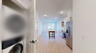 Located at 4010 Entrada Dr in Charlottesville, VA, this thoughtfully designed one-bedroom, one-bathroom single-floor unit offers a clean, modern aesthetic throughout. Light wood laminate flooring runs continuously across the entire space, creating a cohesive and airy feel.

The open-concept kitchen and living area serves as the heart of the unit. The kitchen is outfitted with white shaker-style cabinetry, open display shelving, a white quartz countertop, a stainless steel sink, and a full suite of stainless steel appliances including a refrigerator with ice maker, range, dishwasher, and built-in microwave. Recessed lighting illuminates the kitchen, while a window at the far end of the living area draws in natural light.

The bedroom is a well-proportioned retreat featuring a ceiling fan, windows with outdoor views of surrounding greenery, and access to a private exterior door. A dedicated closet provides organized storage with built-in wire shelving.

The bathroom is finished with a gray modern vanity, white countertop, a large mirror with overhead lighting, and clean tilework. The unit also includes a separate laundry area and pantry, adding practical functionality. Crisp white walls and black hardware accents throughout give the space a fresh, contemporary character.