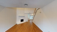 Located at 8003 Woodway in Houston, TX, this two-story residence offers a well-organized layout with distinct living areas spread across both floors. The main level centers around a spacious living room highlighted by a white-painted brick fireplace with a raised hearth, warm hardwood flooring, and an open staircase with wood railing leading to the upper level. French doors at the rear of the main floor flood the space with natural light and provide outdoor access. The adjacent dining area features a pendant light fixture and continues the hardwood flooring, with a pass-through granite countertop connecting to the kitchen. The kitchen is equipped with white cabinetry, granite countertops, black appliances including an electric range and over-the-range microwave, and tile flooring. Bathrooms throughout the home feature granite vanity countertops, framed mirrors, tile flooring, and tub-shower combinations. Upstairs, the bedrooms are carpeted and include ceiling fans with light kits. The primary bedroom is notably well-appointed, offering a walk-in closet with built-in shelving and an additional room with open shelving for extra storage. Secondary bedrooms also feature carpet and ceiling fans, with windows providing views of the surrounding greenery.