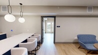 Located at 100 Mia Rose Way in Dardenne Prairie, Missouri, this single-floor meeting and conference space offers a well-appointed environment designed for professional gatherings and collaboration. The layout is thoughtfully divided into distinct functional zones that together create a cohesive and polished atmosphere.

The centerpiece of the space is a formal conference room featuring a large rectangular wood-toned table surrounded by ergonomic white rolling chairs. A wall-mounted flat-screen display anchors one end of the room, complemented by a sleek linear pendant light overhead and light hardwood flooring underfoot. Soft blue-green accent walls add a calm, modern touch against the neutral beige surrounding walls.

Adjacent to the conference room is a relaxed lounge area furnished with contemporary blue upholstered chairs and a rounded wood coffee table, ideal for informal meetings or casual conversations. Recessed ceiling lighting keeps the space bright and welcoming.

A glass-walled private room with dark-framed sliding glass doors provides visual openness while maintaining acoustic separation. This area features patterned carpet flooring and globe pendant lights, offering a distinct setting within the overall layout.

Throughout the space, clean lines, neutral tones, and consistent light wood flooring create a cohesive, professional aesthetic suited for meetings, presentations, and collaborative work sessions.