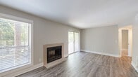 This thoughtfully designed 1-bedroom, 1-bathroom residence offers a comfortable and functional single-floor layout. The living room serves as the centerpiece of the home, showcasing durable wood-look plank flooring, neutral warm-gray walls, and a tile-surround fireplace that adds both character and warmth. Natural light fills the space through multiple windows with blinds and a sliding glass door that opens to an outdoor balcony, providing pleasant views of surrounding greenery.

The kitchen is well-equipped with white shaker-style cabinetry, granite countertops, a light blue subway tile backsplash, stainless steel appliances including a gas range and refrigerator, and matching wood-look flooring that flows seamlessly from the main living area.

The bathroom features a white vanity with granite countertops, a framed mirror, chrome fixtures, and coordinating wood-look flooring, presenting a clean and modern aesthetic. The bedroom offers plush wall-to-wall carpeting, a window with views of the outdoors, and a closet for ample storage. The utility closet houses a water heater and includes wire shelving and washer/dryer hookups. A connecting hallway ties all rooms together, creating a practical and cohesive floor plan throughout.