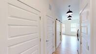 Located at 5111 Abercorn St in Savannah, Georgia, this one-bedroom, one-bathroom unit offers a thoughtfully designed single-floor layout that maximizes every square foot. The interior showcases a clean, modern aesthetic with light hardwood-style flooring running through the main living areas and a bright, neutral color palette throughout.

The combined kitchen and dining area is a standout feature, equipped with rich wood cabinetry, dark granite countertops, a white subway tile backsplash, stainless steel appliances including a range, built-in microwave, and dishwasher, and a deep undermount sink with a contemporary pull-down faucet. The living area benefits from generous natural light through multiple windows fitted with blinds, along with direct exterior access via a glass-panel door.

A hallway connects the main living space to the private areas of the unit, highlighted by a stylish sliding barn door and pendant lighting with matte black dome fixtures. The bedroom features plush carpeting, closet access, and additional storage. The bathroom includes a full soaking tub and shower combo with white tile surround and a curved curtain rod. A dedicated utility room and two closets provide practical storage solutions, rounding out this well-appointed Savannah residence.