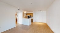This single-floor residence offers a thoughtfully designed open-concept layout that seamlessly connects the living area and kitchen. The living space features light hardwood flooring throughout, crisp white walls, and recessed track lighting, creating a bright and welcoming atmosphere. Large open sightlines from the living area extend toward a sliding door that leads to an outdoor space, allowing natural light to fill the interior.

The kitchen is anchored by a white peninsula with a built-in sink and dishwasher, providing both additional counter space and a natural divider between the cooking and living areas. Warm wood cabinetry, a dark backsplash, and a full suite of stainless steel appliances — including a gas range, over-the-range microwave, and refrigerator — complete the kitchen's modern, functional design.

The bedrooms are carpeted for comfort, finished with clean white walls, and feature windows that bring in natural light. Ample closet space and door access to adjacent rooms add to their practicality.

The bathroom is finished to a high standard, featuring large-format beige floor tiles, a wood-toned vanity with a white countertop, and a combined tub and shower enclosed by a sliding glass door with striking marble-style tile surround. Brushed nickel fixtures and overhead recessed lighting add a refined, contemporary touch throughout.