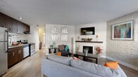 Located at 4701 E Mississippi Ave in Glendale, Colorado, this one-bedroom, one-bathroom residence offers a well-designed single-floor layout that maximizes functionality and style. The open-concept living and kitchen area serves as the heart of the home, where wood-style flooring flows seamlessly underfoot. The living space is anchored by a fireplace with a dark wood mantle and a striking white-painted exposed brick accent wall that adds texture and character to the room. The kitchen is outfitted with dark espresso cabinetry, stainless steel appliances including a refrigerator and range, and is illuminated by track lighting overhead. The bedroom is a comfortable retreat, featuring soft carpeting, a ceiling fan, a window that brings in natural light, and its own white-painted brick accent wall that carries the design language throughout the unit. Two closets provide ample storage, including a sliding-door closet in the bedroom with built-in shelving and hanging rods. A utility room and a full bathroom round out the floor plan. The unit also includes a dedicated entry area with access to the outdoors. Overall, the space presents a cohesive, modern aesthetic with industrial-inspired details.