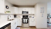 This well-appointed 2-bedroom, 1-bathroom unit in Goffstown, NH offers a functional and comfortable single-floor layout. The combined kitchen and living area serves as the heart of the home, featuring wood-style flooring throughout. The kitchen is equipped with stainless steel appliances—including a range, microwave, and dishwasher—complemented by crisp white cabinetry, light countertops, a tile backsplash, and a skylight that adds bright, natural illumination. A dedicated dining area provides additional convenience. The living room is bright and inviting, highlighted by a sliding glass door that opens to a private balcony overlooking lush outdoor greenery, filling the space with natural light. Both bedrooms are carpeted and comfortably sized, with the primary bedroom offering multiple windows with sheer curtains that allow soft, diffused light. The second bedroom features neutral tones and ample wall space. The full bathroom includes a tub/shower combination, a white vanity, and wood-style flooring, maintaining a clean and cohesive aesthetic. A hallway connects the main living areas to the bedrooms and bathroom, completing this efficiently designed home.