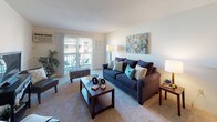 This single-floor, two-bedroom, one-bathroom residence offers a thoughtfully arranged layout with comfortable living spaces throughout. The living room is carpeted and features a sliding glass door that opens to a private balcony, allowing natural light to fill the room and providing outdoor views of the surrounding area. A wall-mounted air conditioning unit and baseboard heating are also present in the living space.

The kitchen is well-equipped with warm-toned wood cabinetry, dark countertops, tile flooring, and white appliances including a gas range, dishwasher, and refrigerator. A sink with a small window above it adds a practical touch to this functional cooking space.

The primary bedroom is generously sized, featuring plush carpeting, a large closet with paneled doors, and a sliding glass door leading directly to the balcony. The second bedroom also offers carpeted flooring, a built-in closet, and large windows that bring in ample natural light, making it suitable as a bedroom or home office.

The bathroom includes a tub-shower combination with blue tile surround, tile flooring, and a wood-toned vanity with a white countertop, completing this comfortable and practical residence.