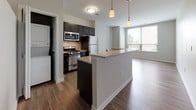 This single-floor residence at 200 College presents a clean, contemporary design with an open-concept layout that connects the kitchen and living areas seamlessly. The kitchen is well-appointed with dark espresso cabinetry, granite countertops, and a full suite of stainless steel appliances including a gas range, microwave, and refrigerator. A peninsula with pendant lighting above serves as both a functional workspace and a natural divider between the kitchen and the open living area, enhancing the sense of flow throughout the space.

Wood-style flooring runs consistently across the main living areas, contributing to a warm yet modern aesthetic. The living space is generously proportioned, with neutral-toned walls and natural light filtering in through a large window that offers views to the exterior. An in-unit stacked washer and dryer adds everyday convenience.

The bathroom is finished with white tile flooring and tiled walls, featuring a full soaking tub with shower, a dark-cabineted vanity, and clean, minimalist fixtures. A louvered closet door provides additional storage access nearby. Overall, the space maintains a cohesive, modern palette with practical finishes suited for comfortable everyday living.
