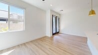Located at 201 W Coolidge St in Phoenix, AZ, this thoughtfully designed one-bedroom, two-bathroom unit offers a clean, modern aesthetic with light wood-style flooring and crisp white walls throughout. The open-concept kitchen serves as the heart of the home, featuring white cabinetry with gold hardware, quartz countertops, a large center island with pendant lighting, stainless steel appliances including a gas range and French door refrigerator, and a striking herringbone tile backsplash. In-unit stacked washer and dryer are conveniently tucked behind a stylish gray door off the kitchen. The living area is bright and welcoming, highlighted by French doors that invite natural light and provide outdoor access. The bedroom is comfortably proportioned, offering a large window with lush exterior views and direct access to a walk-in closet with built-in shelving. The primary bathroom is elegantly appointed with a wide white vanity, quartz countertop, undermount sink, and a large framed mirror framed by double shaker-style doors. A second bathroom features a full tub-shower combo with dark subway tile accents set against marble-style surrounds. A built-in desk in the bedroom area adds functional versatility to this well-appointed Phoenix residence.