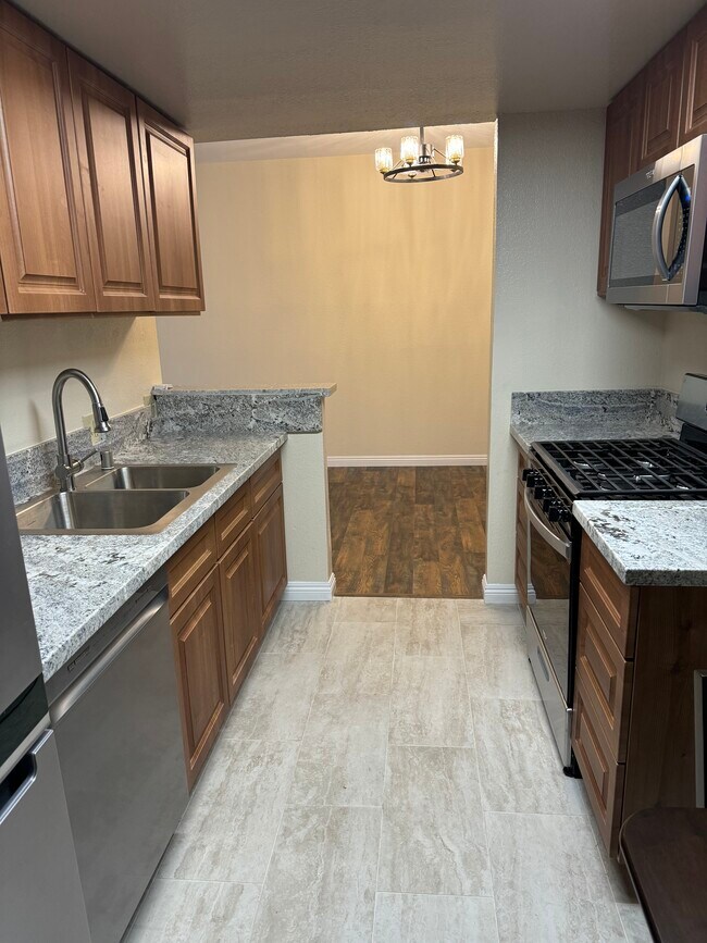 Cocina con electrodomésticos de acero inoxidable, encimeras de mármol y azulejos de porcelana. - 10824 Palms Blvd