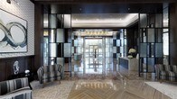 This upscale lobby showcases a refined blend of modern and classic design elements. The flooring is a standout feature, combining richly veined polished marble tiles in warm beige and brown tones with an intricate herringbone-patterned inlay section, adding visual depth and dimension to the space. A coffered ceiling with recessed lighting casts a warm, even glow throughout, enhancing the sophisticated ambiance.

Striking floor-to-ceiling decorative dividers with dark metal framing and textured frosted glass panels define sections of the lobby, creating an elegant visual rhythm while maintaining an open feel. These panels are complemented by dark wall paneling that lines the perimeter, adding contrast and drama to the space.

A sleek marble reception desk anchors one side of the lobby, adorned with fresh floral arrangements. On the opposite side, a striped accent chair provides a comfortable seating area for guests. At the far end, large glass entry doors flood the interior with natural light, offering a view to the outdoors. The overall atmosphere is polished, professional, and welcoming.