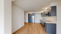 Located at 2365 NE Conners Ave in Bend, Oregon, this modern 1-bedroom, 1-bathroom unit offers a thoughtfully designed single-floor layout. Light-toned hardwood flooring flows throughout the entire space, lending warmth and visual continuity to every room.

The open-concept living, dining, and kitchen area forms the heart of the unit. The kitchen is outfitted with sleek gray flat-front cabinetry extending to the ceiling for ample storage, white countertops, a stainless steel refrigerator, electric range with oven, built-in microwave, and dishwasher — all finished with a clean, contemporary aesthetic. Recessed lighting illuminates the space efficiently.

The living room is bright and airy, with a door providing direct access to a private balcony, bringing in natural light and a connection to the outdoors. The bedroom is a comfortable retreat featuring multiple windows with blinds that fill the room with natural light, along with access to a dedicated closet and a full bathroom. The bathroom is finished in crisp white tones and includes a shower/tub combination and wood-look flooring.

Clean white walls, modern fixtures, and a consistent design palette throughout give this Bend unit a fresh, move-in-ready feel ideal for those seeking contemporary, efficient living.