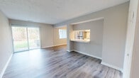 This generously sized single-floor residence offers a thoughtfully designed layout across one bedroom and one bathroom. The open-concept living and dining area is expansive and airy, featuring durable hardwood-style flooring in a cool grey tone, a textured ceiling, and large sliding glass doors that invite abundant natural light while providing views of the surrounding green outdoor area. The kitchen is efficiently arranged in a galley style, equipped with white shaker cabinetry, a classic subway tile backsplash, stainless steel appliances including a full-size refrigerator, and striking marble-look countertops that extend to a pass-through bar, seamlessly connecting the kitchen to the living space. The bedroom is a comfortable retreat with plush carpeting, a window offering natural light, and ample storage provided by a wide double-door closet. The bathroom features clean white cabinetry with brushed nickel hardware, a full shower-tub combination, and warm wood-tone flooring. A dedicated entrance and in-unit laundry connections add everyday convenience. Outside, a patio overlooks an open grassy area, completing this well-appointed and move-in-ready residence.