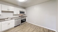 Located at 8-127 Michael Rd in New London, CT, this single-floor, three-bedroom, one-bathroom residence offers a practical and well-maintained layout. The updated kitchen is a standout feature, showcasing crisp white shaker-style cabinetry, granite-look countertops, stainless steel appliances including a refrigerator, electric range, microwave, and dishwasher, all set atop light wood-look flooring. The living area is carpeted and features a large window that brings in natural light. Each of the three bedrooms is finished with soft wall-to-wall carpet and neutral gray walls. The spacious primary bedroom includes a large built-in closet with bi-fold doors and transitions to dark wood-look flooring near the entry. The secondary bedrooms also feature bi-fold closets and windows with outdoor views of the surrounding neighborhood. The full bathroom is clean and functional, equipped with a tub-shower combination, a white vanity with sink, a mirrored medicine cabinet, and wood-look flooring. Baseboard heating is present throughout the bedrooms, ensuring year-round comfort. The overall aesthetic is clean, neutral, and move-in ready.