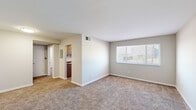 This single-story unit presents a clean, straightforward layout designed for comfortable everyday living. The living area serves as the central gathering space, finished with wall-to-wall carpet in a warm neutral tone and neutral-painted walls that create a bright, open atmosphere. A large window fitted with horizontal blinds allows natural light to fill the room, while a dedicated entryway with hard-surface flooring provides a practical transition point upon entry.

The kitchen is efficiently designed and features contemporary flat-front cabinetry in a warm taupe finish with sleek bar-pull hardware, complemented by a dark granite-style countertop. A stainless steel single-basin sink and a white gas range complete the cooking space, offering a functional environment for meal preparation.

The bedrooms are carpeted and finished in soft, neutral tones, each benefiting from windows that bring in natural light and offer outdoor views. Closet access is provided, adding practical storage within each room.

The bathroom includes a full tub and shower combination with white tile surround, a toilet, and a vanity, all set atop wood-look vinyl flooring. Throughout the unit, consistent neutral finishes, clean lines, and a well-organized floor plan contribute to an overall ambiance that is practical, comfortable, and move-in ready.
