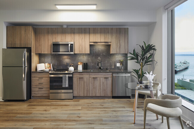 Apartment kitchen with stainless steel appliances, quartz countertops and wood-style flooring. - Griffis Seattle Waterfront