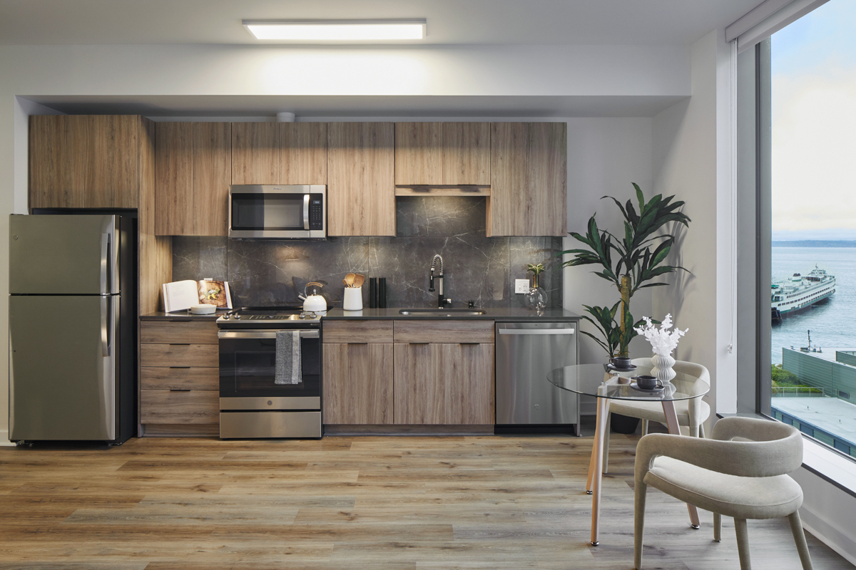 Cocina del apartamento con electrodomésticos de acero inoxidable, encimeras de cuarzo y suelos de madera. - Griffis Seattle Waterfront