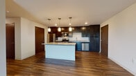 Located at 2747–2759 Novation Pkwy in Fitchburg, Wisconsin, this well-appointed single-floor residence offers a thoughtfully designed layout with modern finishes throughout. The open-concept kitchen serves as the centerpiece of the space, showcasing rich dark cabinetry that extends to the ceiling, granite countertops, and a full suite of stainless steel appliances including a refrigerator, range, built-in microwave, and dishwasher. A central island with matching granite provides additional prep space and a natural gathering point, while stylish pendant lighting overhead adds a warm, contemporary ambiance. Durable hardwood-style flooring runs throughout the main living areas, lending a cohesive and polished look. The spacious living area features neutral walls and a large window that invites natural light and offers views of the surrounding greenery. The bedroom is generously sized, finished with plush carpet, and includes a closet with built-in shelving. Two bathrooms serve the unit: one featuring a walk-in shower and the other a full soaking tub, both appointed with dark vanity cabinetry, light tile flooring, and clean white fixtures. The overall design balances modern aesthetics with functional living across every area of the space.