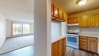 Located at 460 Fifth Ave N in Hopkins, Minnesota, this two-bedroom, three-bathroom home offers a practical and comfortable single-floor layout. The kitchen is well-appointed with warm honey-toned wood cabinetry, a gas range, white appliances including a dishwasher and refrigerator, and a pass-through counter that connects seamlessly to the dining area — ideal for everyday convenience. Hard surface flooring in the kitchen transitions naturally into the adjacent living spaces.

The living room is bright and welcoming, featuring plush carpeting, a sliding glass door that opens to a balcony, and a large window that fills the room with natural light and outdoor views of surrounding greenery. Each bedroom is carpeted and well-sized, with the primary bedroom offering generous proportions and ample closet space. A standout feature is the walk-in closet with dual shelving rods, providing excellent storage capacity. A second bedroom includes a window with outdoor views and baseboard heating.

Three bathrooms serve the home, including one with a standalone walk-in shower and tile flooring, and another featuring a wood-toned vanity with a wide mirror and overhead lighting. Throughout the home, warm wood trim accents neutral walls and textured ceilings, creating a cohesive and functional living environment.