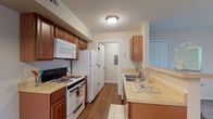 Located at 990 Plumway Ln in Lewis Center, Ohio, this single-floor residence offers a well-organized and functional layout suited for comfortable everyday living. The galley-style kitchen is equipped with warm wood cabinetry, a gas range, built-in microwave, full-size refrigerator, and a double sink with light-toned countertops. Wood-style flooring runs throughout the kitchen and connecting hallway, adding a cohesive, clean aesthetic. A pass-through opening connects the kitchen to the dining and living areas, promoting an open feel between spaces. The living room features neutral carpeting and a sliding glass door that fills the room with natural light and provides access to an outdoor area. Bedrooms are carpeted and finished in soft neutral tones, each offering closet storage. One bedroom includes a ceiling fan with light fixture, while another features a window with views of the surrounding greenery. The unit includes two bathrooms: one with a vanity, toilet, and wood-toned cabinetry, and a second with a shower-tub combo. Throughout the space, consistent neutral wall colors and clean finishes create a calm, move-in-ready atmosphere.