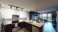 Located at 1633 N Pearl St in Denver's Capitol Hill neighborhood, this thoughtfully designed one-bedroom, one-bathroom residence offers a well-appointed single-floor layout with modern finishes throughout. The open-concept living area is anchored by rich hardwood-style flooring and a bold navy accent wall, creating a vibrant yet cohesive atmosphere. A sliding glass door leads to a private outdoor space, where views of the Denver skyline frame the living room beautifully.

The kitchen is a standout, featuring dark lower cabinetry contrasted by sleek white upper cabinets, a classic subway tile backsplash, stone countertops, and a full suite of stainless steel appliances including a range, microwave, dishwasher, and French door refrigerator. Pendant lighting over the peninsula adds a contemporary touch. A dining area sits adjacent to the kitchen, completing the open living space.

The bedroom offers a warm, earthy palette with a striking terracotta accent wall and two windows dressed in sheer yellow curtains that fill the room with natural light. The bathroom features tile flooring, stone-topped vanity, and direct access to a walk-in closet. Track lighting and recessed fixtures throughout add to the unit's modern, polished character.