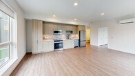 This 990-square-foot, single-floor apartment at 16855 Redmond Way, Unit 326, Redmond, WA features a thoughtfully designed open-concept layout with 2 bedrooms and 2 bathrooms. Wide-plank wood-style flooring flows throughout, complementing the clean, modern aesthetic of the space.

The combined kitchen and living area serves as the heart of the unit. The kitchen is outfitted with stainless steel appliances — including a French door refrigerator, range, microwave, and dishwasher — paired with two-tone cabinetry in light wood and gray tones, a tile backsplash, and recessed lighting. The open living area features a large window providing natural light and outdoor views.

The primary bedroom spans 170 square feet and includes a ceiling fan and a large window with outdoor views. The second bedroom similarly features a ceiling fan and a generous window overlooking a courtyard with a pool. Both bathrooms are finished with white subway-style tile tub/shower surrounds, matte black fixtures and hardware, wood-style flooring, and light wood vanities.

A dedicated laundry area houses a full stacked washer and dryer. A wall-mounted mini-split HVAC system provides efficient climate control throughout the unit.