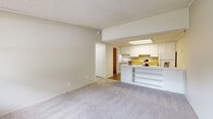 Located at 102 Hartford Run in Buford, Georgia, this single-floor residence offers a practical and efficient layout across six distinct spaces: a living room, bedroom, kitchen, bathroom, utility room, and hallway. The living room greets you at entry with soft carpeting underfoot, neutral-toned walls, a textured ceiling, and a large window that invites natural light and outdoor views. It connects seamlessly to the kitchen via a peninsula-style counter with open shelving below, providing added storage and a natural dividing feature between the two spaces. The kitchen is well-equipped with white cabinetry reaching toward the ceiling, a yellow laminate countertop, a built-in range, refrigerator, and a recessed overhead light fixture. Hardwood-style flooring adds warmth to this area. The bedroom is a comfortably sized, quiet retreat with plush carpeting, a window for natural light, crown molding, and a spacious reach-in closet with double doors. The full bathroom features light wood-look tile flooring, a combined tub and shower, a toilet, and a single vanity with a marble-patterned countertop. A utility room and connecting hallway complete this well-organized, easy-to-navigate home.