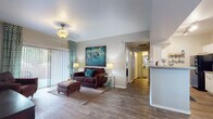 This single-story residence offers a thoughtfully designed layout that balances comfort and functionality across several distinct living areas. The living room serves as the heart of the home, featuring wood-look flooring, a ceiling fan, and a sliding glass door that floods the space with natural light while providing direct access to an outdoor patio area. The open flow connects seamlessly to the rest of the unit, creating an inviting and airy atmosphere.

The galley-style kitchen is efficiently organized with ample white cabinetry, granite-style countertops, a double basin sink, and a full suite of black appliances including a refrigerator, electric range, microwave, and dishwasher. Adjacent to the kitchen, the dining area features wood-look flooring, a pendant light fixture, large windows with decorative curtains, and tall accent mirrors that enhance the sense of space.

Both bedrooms are carpeted and generously sized, each equipped with ceiling fans, large windows with outdoor views, and ample natural light. The full bathroom includes white cabinetry, granite-style countertops, a wide vanity mirror, and a full tub-shower combination with wood-look tile flooring. A dedicated in-unit laundry room accommodates a full-size washer and dryer with overhead shelving for added storage.