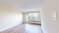 Located at 267 St George St, Suite 905, in Toronto's vibrant Annex neighbourhood, this efficiently designed studio unit offers a thoughtful use of space across a single floor. The living area is finished with warm, light-toned hardwood flooring that runs throughout, contributing to a clean and cohesive aesthetic. Crisp white walls and white baseboards enhance the brightness of the space, while large windows along one wall allow generous natural light to fill the room and offer views of the surrounding cityscape and neighbouring buildings. A private balcony accessible from the main living area extends the sense of openness and provides an elevated outdoor retreat with treetop and city views. The compact kitchenette is neatly integrated into the layout, featuring white cabinetry overhead, a white range, and a window that brings in additional natural light. Radiant baseboard heating is present along the window wall, ensuring comfort year-round. The bathroom is finished with classic white subway-style wall tiling and includes standard fixtures, maintaining the clean, minimalist palette of the unit. Multiple interior doors provide access to closet storage, optimizing functionality within the footprint. The overall ambiance is bright, clean, and practical — well-suited for urban living in one of Toronto's most walkable and sought-after neighbourhoods.