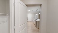 This 1,050 square foot single-story residence offers a well-designed layout with 2 bedrooms, 2 bathrooms, and 4 closets, all connected by two hallways. Light hardwood-style flooring flows consistently throughout every room, contributing to a bright, cohesive aesthetic.

The open-concept kitchen and living area serves as the heart of the unit. The kitchen is outfitted with a large center island featuring a white quartz countertop, undermount sink, and pendant lighting above. White cabinetry, a subway tile backsplash, and stainless steel appliances — including a refrigerator, microwave, and range — complete the modern look.

The primary bedroom measures 150 square feet and includes a ceiling fan and access to a private en suite bathroom. The en suite features light wood cabinetry, a white countertop vanity, and hardwood-style flooring. The second bathroom includes a full tub-shower combo with built-in shelving and an overhead cabinet for storage.

The second bedroom benefits from natural light through a window with blinds and includes its own ceiling fan. Both bedrooms offer closet access and a neutral taupe color palette that complements the overall design. The unit's clean finishes, ample storage, and consistent flooring create a functional and contemporary living environment.