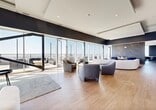 Located in the heart of downtown Edmonton at 104 Street NW, this elevated rooftop lounge offers a refined and contemporary setting across a generous single-floor layout. Floor-to-ceiling glass walls flood the living area with natural light while framing panoramic views of the Edmonton skyline, seamlessly blending the interior and exterior spaces.

The open living room is anchored by warm hardwood flooring and features multiple distinct seating arrangements, including plush tufted sofas and curved accent chairs. A dramatic floor-to-ceiling slab of veined marble serves as a striking focal point, complemented by a sleek fireplace, lending the space an air of sophistication. High ceilings and expansive glazing further enhance the sense of openness.

The kitchen is a standout, boasting slatted wood ceiling detailing, light cabinetry, a bold dark marble backsplash, stainless steel appliances, and a large central island with bar seating—ideal for both entertaining and everyday use.

The outdoor terrace is equally impressive, offering generous poured-concrete patio space furnished with lounge seating, a central fire pit, and dining areas, all set against an unobstructed view of the Edmonton cityscape. Large sliding glass doors connect the terrace directly to the interior, making this space as functional as it is visually captivating.