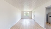 Located in Crittenden, Kentucky, this well-appointed single-floor home offers 2 bedrooms and 2 bathrooms within a thoughtfully laid-out floor plan. The living room greets you with light wood-look flooring, crisp white walls, a textured ceiling, and an abundance of natural light streaming through a large window and glass-paneled entry door — creating an open and airy atmosphere. A secondary entry area provides additional access and continuity throughout the home. The kitchen is a functional highlight, featuring contemporary flat-front grey cabinetry, white quartz-style countertops, and a full suite of stainless steel appliances including a refrigerator, electric range, and dishwasher. A window above the sink brings in natural light, enhancing the clean, modern aesthetic. Both bedrooms are comfortably sized, with the spacious primary bedroom offering ample room and natural light from well-placed windows. The light hardwood-style flooring carries consistently throughout the bedrooms, adding warmth and cohesion. Each of the two bathrooms is equipped with a full tub-shower combination with chrome fixtures. A dedicated utility room and hallway round out the practical layout, making this home as functional as it is inviting.