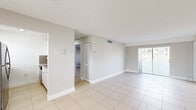 Located at 3847 NE 168th St in North Miami Beach, FL, this 2-bedroom, 1-bathroom residence offers a clean, bright layout across a single floor. Light-toned large-format ceramic tile flows consistently throughout every room, creating a cohesive and easy-to-maintain living environment.

The open living room is generously proportioned, featuring neutral gray walls, white baseboards, and sliding glass doors that invite natural light and provide access to an outdoor balcony area with views of the surrounding neighborhood. The space connects seamlessly to the galley-style kitchen, which is outfitted with white cabinetry, granite-style countertops, a speckled tile backsplash, stainless steel appliances including a refrigerator and range, and a built-in dishwasher.

The primary bedroom is spacious, offering louvered bi-fold closet doors and ample room for furnishings. The second bedroom features a ceiling fan with light fixture, a louvered closet, and a window that brings in natural light. Both rooms maintain the consistent neutral palette found throughout the home.

The full bathroom includes a white vanity with granite-style countertop, an undermount sink, and a separate shower and tub enclosure with a privacy window. A connecting hallway ties all rooms together efficiently, completing this well-organized and functional floor plan.