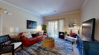 This thoughtfully designed one-bedroom, one-bathroom residence in Kansas City, Missouri offers a practical and comfortable single-floor layout. The open-concept living and dining area is bright and welcoming, featuring crown molding, neutral tones, and sliding glass doors that invite natural light while providing outdoor access. The kitchen is efficiently laid out in a galley style, equipped with stainless steel appliances including a refrigerator, electric range, and microwave, complemented by dark granite-style countertops, light wood cabinetry, tile flooring, and a breakfast bar with seating for two. The spacious bedroom accommodates a full-sized bed comfortably, with plush carpeting, generous window views of lush greenery, and access to multiple closets offering abundant storage. The bathroom features tile flooring, a long vanity with wood cabinetry, and a shower-tub combination. A dedicated in-unit laundry room houses a full-sized washer and dryer with overhead shelving. Additional spaces include a hallway, office, and utility room, rounding out the functional floor plan. Throughout the residence, a consistent warm, neutral palette and carpet-to-tile flooring transition create a cohesive and inviting atmosphere.