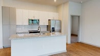 Located at 7311 Baymeadows Way in Jacksonville, FL, this two-bedroom, three-bathroom single-floor residence offers a clean, modern aesthetic with thoughtful design details throughout. Wood-style flooring flows consistently across the living areas, hallway, and bedrooms, creating a cohesive and easy-to-maintain interior.

The kitchen is a standout feature, showcasing a large granite-topped island with an undermount sink, crisp white cabinetry extending to the ceiling, a subway tile backsplash, and a full suite of stainless steel appliances including a French door refrigerator, electric range, and over-the-range microwave. The open layout connects the kitchen seamlessly to the living area, which benefits from multiple windows that invite an abundance of natural light and views of the surrounding greenery.

Each bedroom is generously proportioned, with the primary bedroom offering walk-in closet storage equipped with wire shelving systems. Three closets in total provide ample storage throughout the unit. The three bathrooms are finished with granite vanity countertops, white subway tile surrounds, and wood-style flooring. A dedicated laundry area adds everyday convenience. The bright, neutral color palette and clean finishes give the entire space a fresh, move-in-ready feel.