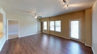 This single-floor residence offers a practical and comfortable layout designed for everyday living. The living area is a welcoming, open space featuring rich hardwood-style flooring, a ceiling fan, and track lighting overhead. Multiple windows along the exterior wall, along with a door to the outside, allow natural light to fill the room. Adjacent to the living area is a built-in shelving nook and a smooth transition into the kitchen.

The kitchen is well-equipped with light wood cabinetry, laminate countertops, tile flooring, and stainless steel appliances including an electric range with an over-the-range microwave and a refrigerator. A double basin sink and generous counter space make this kitchen highly functional.

The bedrooms are carpeted and each feature ceiling fans for comfort. One bedroom includes a walk-in closet with built-in shelving, while others offer window views and ample space. The warm, neutral tones throughout the bedrooms create a calm and restful atmosphere.

The bathroom is outfitted with tile flooring, a vanity with a single sink and light countertop, a large mirror, wall-mounted lighting, a toilet, and a full tub and shower combination with a decorative tile accent border and an overhead cabinet for additional storage.
