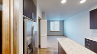 Located at 252 Broadway in downtown Tacoma, Washington, Unit 303 is a thoughtfully designed one-bedroom, one-bathroom residence that makes efficient use of its compact footprint. The open-concept kitchen serves as a central highlight, featuring rich dark-espresso cabinetry, stone-look countertops, and a full suite of stainless steel appliances including a range, over-the-range microwave, and dishwasher. A kitchen island provides additional prep space and a natural transition into the living area. Light wood-tone flooring flows throughout the main living and kitchen areas, adding warmth and visual continuity. The bedroom is carpeted for comfort and includes window blinds that allow for natural light while maintaining privacy, with views of the surrounding urban streetscape. The bathroom is well-appointed with a long granite-topped vanity, wood-framed mirror, and light wood flooring that complements the rest of the unit. A dedicated closet provides practical storage. Warm wood door and window trim is a consistent design detail throughout, adding a refined touch to the clean, neutral palette. Recessed lighting in the kitchen enhances functionality and ambiance. The unit is situated on the third floor, offering a quiet residential experience in a vibrant downtown Tacoma location.