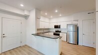 Located in Newberg, Oregon, this thoughtfully designed one-bedroom, one-bathroom unit offers a clean, modern aesthetic throughout its single floor. Light-toned luxury vinyl plank flooring runs seamlessly across all rooms, complementing the crisp white walls and creating a bright, cohesive feel.

The open-concept living, dining, and kitchen area forms the heart of the unit. The kitchen is well-appointed with white shaker-style cabinetry, dark countertops, a subway tile backsplash, recessed lighting, and a full suite of stainless steel appliances including a refrigerator, range, and microwave. A peninsula with an overhang provides additional prep space and casual dining. The living area receives natural light through a window and patio door that opens directly to a private outdoor patio.

The bedroom is a comfortable, well-proportioned space with its own closet and direct access to additional storage. Two closets in total offer practical storage throughout the unit. A dedicated laundry area and pantry add further convenience.

The full bathroom features a white vanity with dark countertop, a shower/tub combination, and light, neutral finishes consistent with the rest of the unit. The overall design is clean and functional, making efficient use of the available space.