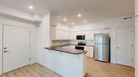 Located in Newberg, Oregon, this thoughtfully designed one-bedroom, one-bathroom unit offers a clean, modern aesthetic throughout its single floor. Light-toned luxury vinyl plank flooring runs seamlessly across all rooms, complementing the crisp white walls and creating a bright, cohesive feel.

The open-concept living, dining, and kitchen area forms the heart of the unit. The kitchen is well-appointed with white shaker-style cabinetry, dark countertops, a subway tile backsplash, recessed lighting, and a full suite of stainless steel appliances including a refrigerator, range, and microwave. A peninsula with an overhang provides additional prep space and casual dining. The living area receives natural light through a window and patio door that opens directly to a private outdoor patio.

The bedroom is a comfortable, well-proportioned space with its own closet and direct access to additional storage. Two closets in total offer practical storage throughout the unit. A dedicated laundry area and pantry add further convenience.

The full bathroom features a white vanity with dark countertop, a shower/tub combination, and light, neutral finishes consistent with the rest of the unit. The overall design is clean and functional, making efficient use of the available space.