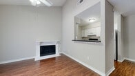 This two-bedroom, two-bathroom two-story home is thoughtfully laid out across two floors, with the majority of the living space on the main level. The living room is a standout, boasting soaring vaulted ceilings, a ceiling fan, and a classic white-mantled wood-burning fireplace that serves as a natural focal point. Rich hardwood-style flooring runs throughout the main level, complementing the neutral gray walls for a clean, cohesive aesthetic. A sliding glass door floods the living area with natural light and provides access to an outdoor space with greenery views. The kitchen features white cabinetry, dark granite-style countertops, a double basin sink, and white appliances, and connects to the living and dining areas via a convenient pass-through window. Both bathrooms are finished with white tub-shower combos, dark countertop vanities, and hardwood-style flooring. Upstairs, the bedrooms are carpeted and well-lit with natural light from large windows offering leafy outdoor views. The spacious primary bedroom includes a walk-in closet with built-in shelving. A dedicated hallway, staircase, and closet round out the functional layout of this well-appointed two-story home.