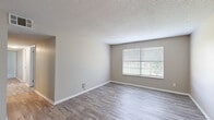 Located at 5000 Harbour Lake Dr in Goose Creek, South Carolina, this single-floor, three-bedroom, two-bathroom home offers a practical and well-appointed layout. The open living room and kitchen area serves as the heart of the home, featuring light-toned luxury vinyl plank flooring, neutral wall tones, and a ceiling fan that enhances airflow throughout the space. Natural light filters in through slatted blinds, creating a bright and welcoming atmosphere.

The galley-style kitchen is a standout feature, equipped with crisp white cabinetry, sleek brushed-nickel hardware, and marble-look countertops that lend a modern aesthetic. Stainless steel appliances, including a refrigerator and range, complement the clean design, while a peninsula provides additional counter space and connects the kitchen to the living area.

The three bedrooms are carpeted for comfort, with windows allowing natural light and views of the surrounding greenery. The primary bedroom offers a generous footprint with access to the hallway. Both bathrooms are finished with wood-look flooring and include tub-shower combinations with clean white surrounds. A dedicated closet with built-in shelving provides practical storage, and textured ceilings are consistent throughout the home.