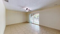 This single-floor, 4-bedroom, 2-bathroom home offers a practical and well-organized layout designed to maximize comfort and utility. The living room is a bright, open space featuring light ceramic tile flooring, a ceiling fan with light fixture, a textured ceiling, and a sliding glass door that opens to a private balcony overlooking lush greenery, allowing natural light to fill the room. The kitchen is conveniently positioned within the floor plan, providing easy access to the main living areas. The four bedrooms are carpeted and each equipped with ceiling fans, offering a cozy and comfortable atmosphere. Several bedrooms feature sliding closet doors, and the primary bedroom includes its own dedicated closet space. With a total of six closets throughout the home, storage is plentiful. The two bathrooms are finished with light tile flooring; one includes a full tub-shower combination with white square tile surround and chrome fixtures, while the other features a vanity with an undermount sink, mirrored medicine cabinet, and overhead lighting. Hallways connect the spaces efficiently, and the overall interior palette of soft neutral tones throughout creates a clean, cohesive aesthetic. Textured ceilings are consistent throughout the home, adding a classic residential character.
