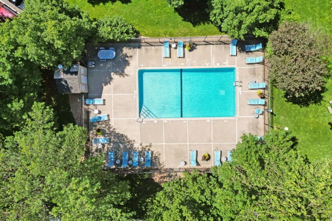 An aerial view of a swimming pool surrounded by trees. - Westwind Apartments