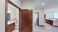 This thoughtfully designed single-floor residence offers two bedrooms and two full bathrooms within a generously sized layout. A neutral color palette, light wood-look flooring, and rich dark wood trim create a cohesive aesthetic throughout the unit.

The open-concept living, dining, and kitchen area serves as the heart of the home. The kitchen is outfitted with dark wood cabinetry, stainless steel appliances including a French door refrigerator, light quartz countertops, a large island with a stainless sink, and pendant lighting. Recessed lighting adds additional illumination throughout. The adjacent living area is bathed in natural light from a bank of large windows and features a sliding glass door with transom windows that opens to a private balcony with views of the surrounding neighborhood.

Both bedrooms feature plush carpeting, generous windows with outdoor views, and ceiling fans for added comfort. The primary bedroom is well-proportioned and includes convenient closet access. Both bathrooms are finished with tile flooring, dark wood vanities, white countertops, and contemporary fixtures. The primary bath features a dual-sink vanity and a tall storage cabinet, while the second bathroom includes a glass-door shower. A dedicated utility room completes the layout.